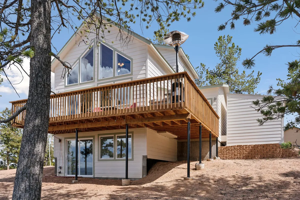 A spacious balcony featuring triangular windows overlooks a lush natural landscape of trees. The balcony is equipped for outdoor relaxation and gatherings, making it ideal for activities such as barbecuing, enjoying coffee, or simply taking in the views. The setting merges indoor comfort with outdoor beauty, highlighting the home’s connection to nature.
