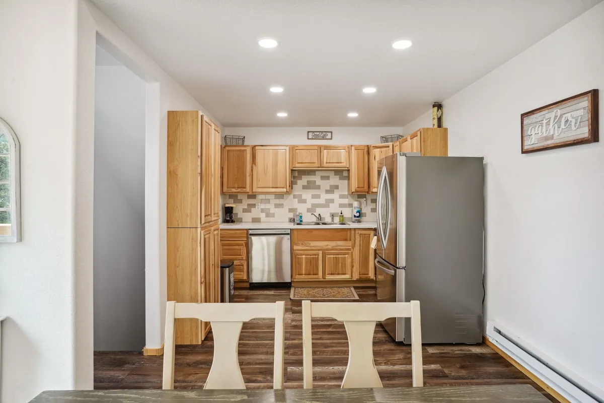 A bright kitchen and dining area with kitchen cabinetry, stainless steel appliances, a dining table, and a stylish tile design on the back wall. The setup invites family meals and gatherings, with the dining area seamlessly connected to the kitchen.